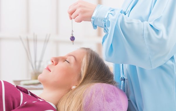 Alternative medicine therapist using pendulum to make a diagnosis